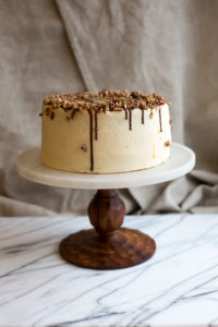 The Mad Hatter's Turtle Cake with caramel buttercream, salted caramel, and toasted pecans on a serving dish.