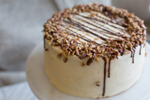 The Mad Hatter's Turtle Cake with caramel buttercream, salted caramel, and toasted pecans on a serving dish.