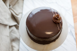 The Mad Hatter's dark chocolate cake coated in chocolate buttercream, and poured dark chocolate ganache on a serving tray.