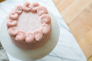 The Mad Hatter's Strawberry white cake with with strawberry buttercream icing on a serving platter.