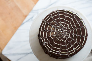 The Mad Hatter's Boston Cream Cake with dark chocolate fudge icing, and poured chocolate ganache on a serving dish.