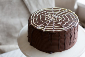 The Mad Hatter's Boston Cream Cake with dark chocolate fudge icing, and poured chocolate ganache on a serving dish.