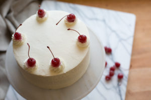 The Mad Hatter's Black Forest Cake, coated in whip cream, chocolate shavings, and cherries on a serving dish.