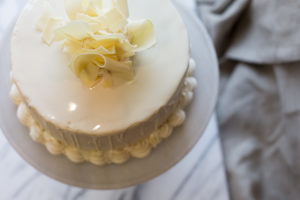 The Mad Hatter's White Lace Cake with white chocolate ganache and vanilla icing on a serving dish.