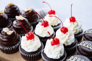 The Mad Hatter's Black Forest Cupcakes on a wooden cutting board.