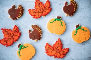 Thanksgiving-themed short dough cookies shaped like pumpkins, turkeys, and autumn leaves