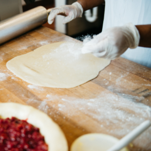 Chef preparing handmade pie dough with flour on wooden surface at Mad Hatter Cafe & Bakeshop in Durham