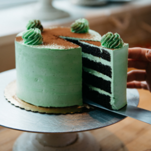 Striking green mint cake with black chocolate layers, topped with succulent decorations, served at Mad Hatter Cafe & Bakeshop in Durham
