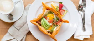 Egg and avocado breakfast bowl with fresh salsa, served alongside a creamy cappuccino at Mad Hatter Cafe & Bakeshop in Durham