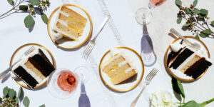Outdoor gourmet cake tasting with vanilla and chocolate layered cakes, served on gold-rimmed plates at Mad Hatter Cafe & Bakeshop in Durham, paired with wine.