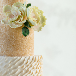 Elegant two-tier wedding cake with sugar flowers and ruffled icing detail, crafted at Mad Hatter Cafe & Bakeshop in Durham
