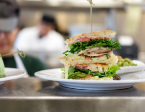 Freshly prepared gourmet sandwich with layers of turkey, fresh greens, and ripe tomatoes, served at Mad Hatter Cafe & Bakeshop in Durham