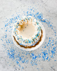 Elegant custom graduation cake with blue and white sprinkles, perfect for celebrating your special day, available at Mad Hatter Cafe & Bakeshop in Durham
