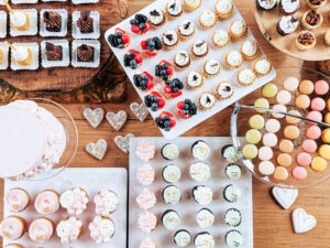 Elegant wedding mini dessert bar with an assortment of mini cupcakes, macarons, and tarts.