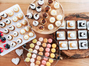 Assorted mini desserts including tarts, macarons, and cupcakes displayed for a wedding dessert table