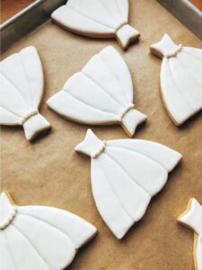 A series of wedding dress themed cookies on a baking tray.