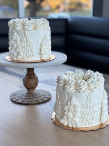 Holiday cake with white frosting and pine-tree decoration.